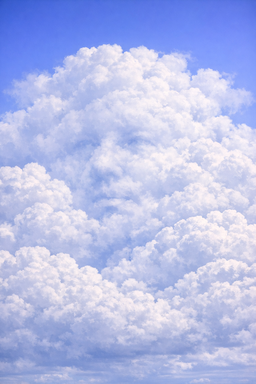 A cloud formation with a subtle human face visible in the billowing white clouds against a blue sky